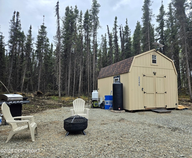 2246 S Fian Dr, Wasilla, AK 99654 - view of shed with an outdoor fire pit and a forest view