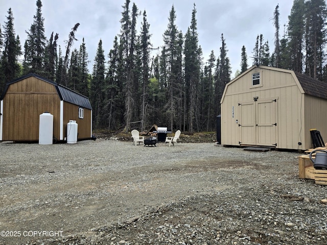 2246 S Fian Dr, Wasilla, AK 99654 - view of shed with an outdoor fire pit and a forest view