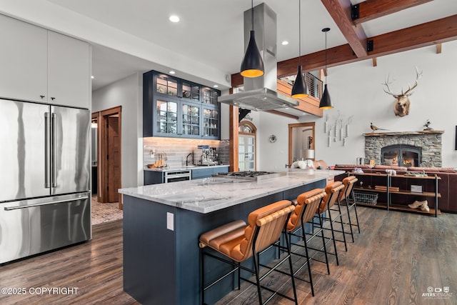 52619 Chumelina Ct, Kasilof, AK 99610 - kitchen featuring appliances with stainless steel finishes, island exhaust hood, dark wood-style flooring, light stone countertops, and decorative backsplash
