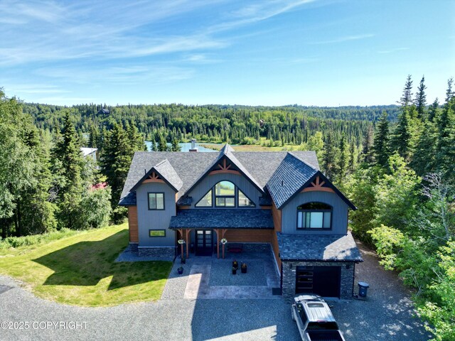 52619 Chumelina Ct, Kasilof, AK 99610 - view of front of house with a forest view, asphalt driveway, an attached garage, a front lawn, and stone siding
