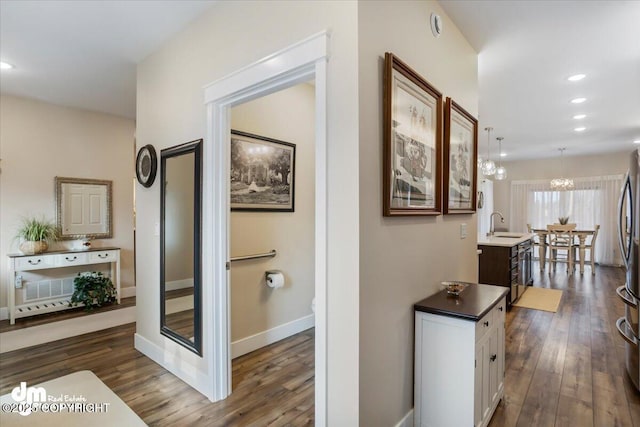 1630 S Corwin Ln, Wasilla, AK 99654 - hall featuring dark wood-style floors, a chandelier, recessed lighting, baseboards, and a sink
