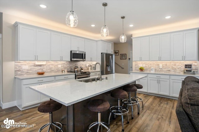 1630 S Corwin Ln, Wasilla, AK 99654 - kitchen featuring stainless steel appliances, a sink, a breakfast bar, decorative backsplash, and wood finished floors