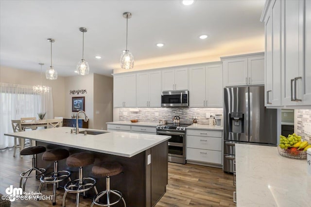 1630 S Corwin Ln, Wasilla, AK 99654 - kitchen with appliances with stainless steel finishes, a sink, tasteful backsplash, a breakfast bar, and wood finished floors