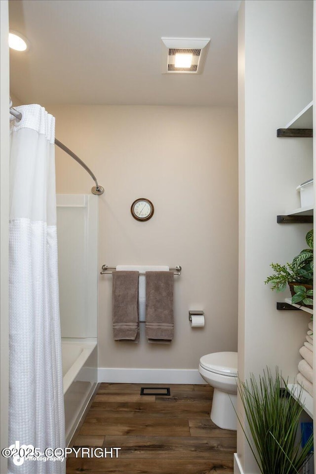 1630 S Corwin Ln, Wasilla, AK 99654 - full bathroom featuring wood finished floors, baseboards, shower / bath combo with shower curtain, and toilet