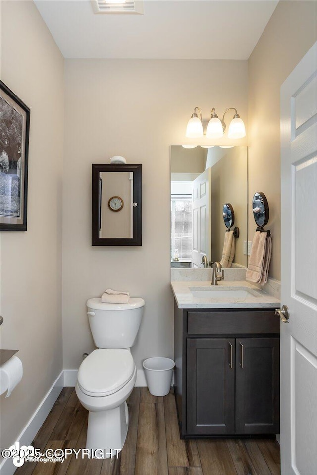 1630 S Corwin Ln, Wasilla, AK 99654 - half bathroom featuring toilet, vanity, wood finished floors, and baseboards