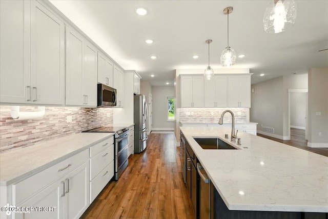 1630 S Corwin Ln, Wasilla, AK 99654 - kitchen featuring appliances with stainless steel finishes, a center island with sink, recessed lighting, hardwood / wood-style flooring, and tasteful backsplash