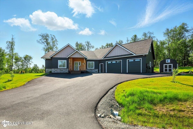 1630 S Corwin Ln, Wasilla, AK 99654 - view of front of house featuring an attached garage, a storage shed, board and batten siding, asphalt driveway, and a front lawn