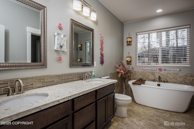 6552 N Michelle Rae St, Wasilla, AK 99654 - bathroom featuring double vanity, a freestanding bath, toilet, and decorative backsplash