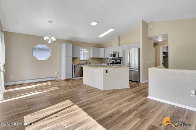 3233 Tayshee Cir, Anchorage, AK 99504 - kitchen featuring stainless steel appliances, a baseboard radiator, a chandelier, a kitchen island, and light wood finished floors
