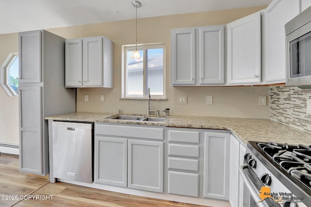3233 Tayshee Cir, Anchorage, AK 99504 - kitchen with appliances with stainless steel finishes, a sink, a baseboard heating unit, hanging light fixtures, and light wood-style flooring