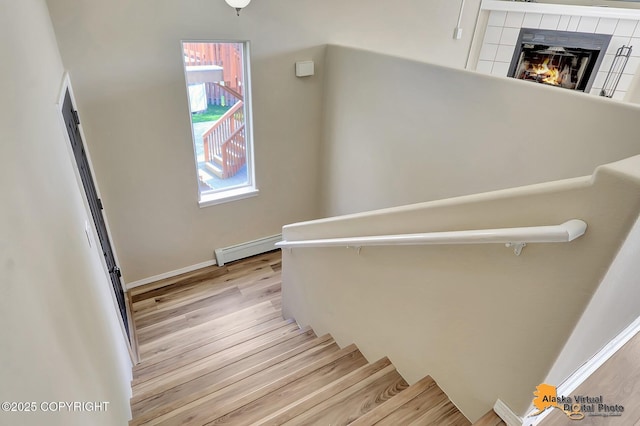 3233 Tayshee Cir, Anchorage, AK 99504 - stairway featuring a baseboard radiator, wood finished floors, a fireplace, and baseboards