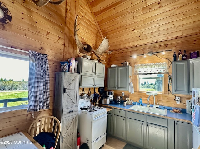 31795 Whiskey Gulch St, Anchor Point, AK 99556 - kitchen with a sink, white range with gas cooktop, wood walls, vaulted ceiling, and plenty of natural light
