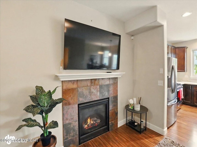 20182 Eagles Nest Ct # 5B, Eagle River, AK 99577 - detailed view of wood finished floors, a fireplace, stainless steel fridge with ice dispenser, baseboards, and range with gas stovetop