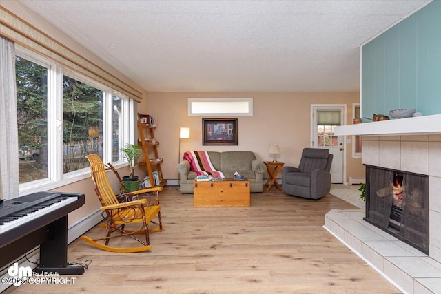 1920 E 56th Ave, Anchorage, AK 99507 - living room featuring light wood-style floors, a fireplace, baseboard heating, a textured ceiling, and a baseboard heating unit