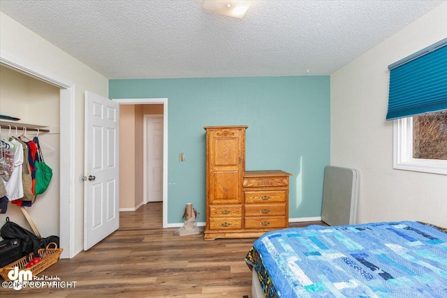 1920 E 56th Ave, Anchorage, AK 99507 - bedroom with wood finished floors, a textured ceiling, baseboards, and a closet