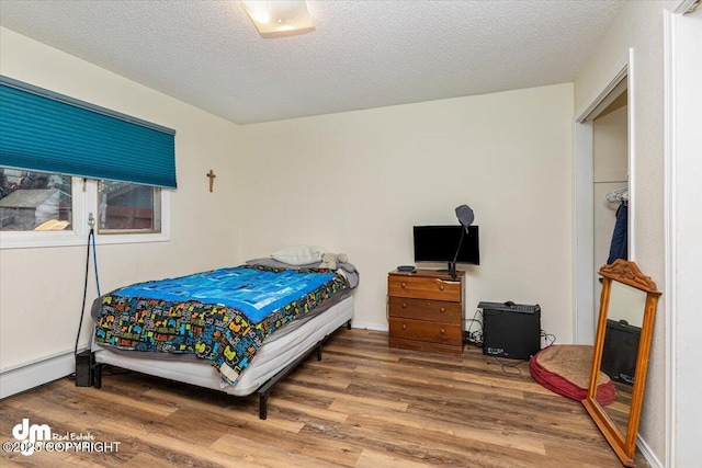 1920 E 56th Ave, Anchorage, AK 99507 - bedroom featuring wood finished floors, a baseboard heating unit, and a textured ceiling