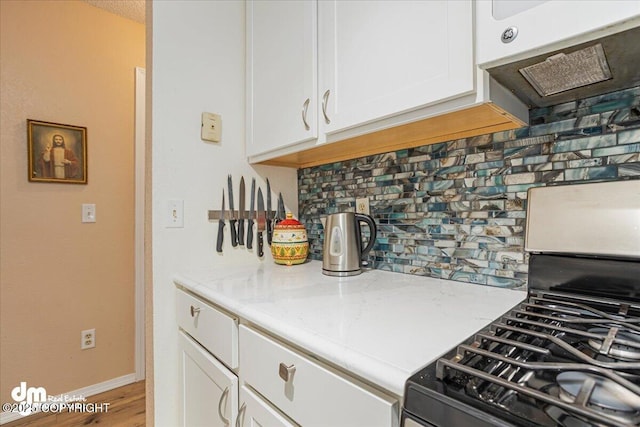 1920 E 56th Ave, Anchorage, AK 99507 - kitchen featuring tasteful backsplash, white cabinets, ventilation hood, stainless steel gas range oven, and light stone counters