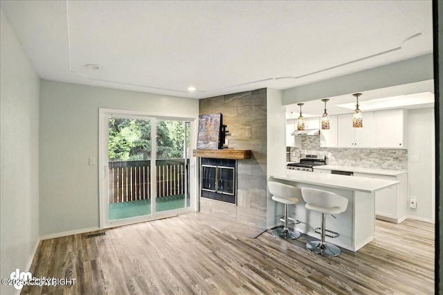 7341 Huntsmen Cir Unit 19C, Anchorage, AK 99518 - kitchen with gas stove, light wood-style floors, white cabinets, light countertops, and under cabinet range hood