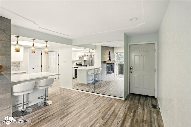 7341 Huntsmen Cir Unit 19C, Anchorage, AK 99518 - kitchen featuring a breakfast bar area, wood finished floors, tasteful backsplash, and white cabinets