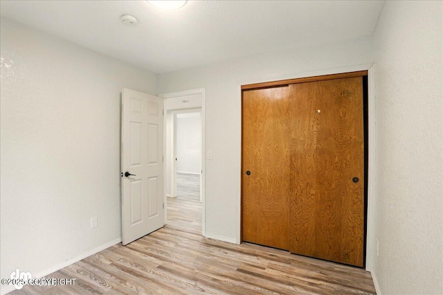 7341 Huntsmen Cir Unit 19C, Anchorage, AK 99518 - unfurnished bedroom featuring wood finished floors, baseboards, and a closet