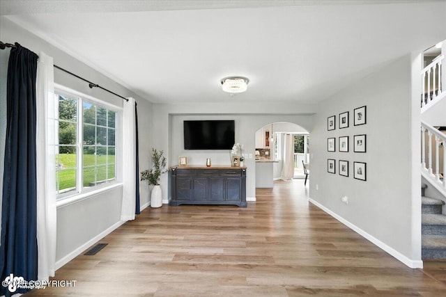 2213 N Tabasco Cat Dr, Palmer, AK 99645 - unfurnished living room with arched walkways, light wood-style floors, and stairs