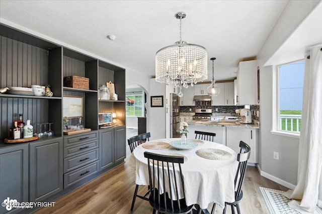 2213 N Tabasco Cat Dr, Palmer, AK 99645 - dining room featuring arched walkways, wood finished floors, healthy amount of natural light, and a chandelier