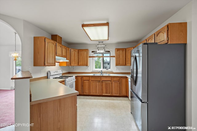 10931 Adanak Cir, Eagle River, AK 99577 - kitchen with freestanding refrigerator, white range with gas stovetop, a sink, a chandelier, and a peninsula