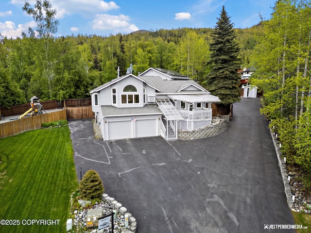 10931 Adanak Cir, Eagle River, AK 99577 - view of front of house with a forest view, an attached garage, stairs, driveway, and roof with shingles