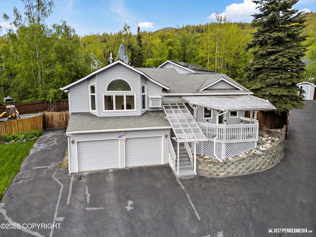 10931 Adanak Cir, Eagle River, AK 99577 - view of front facade featuring asphalt driveway, a wooded view, roof with shingles, and an attached garage
