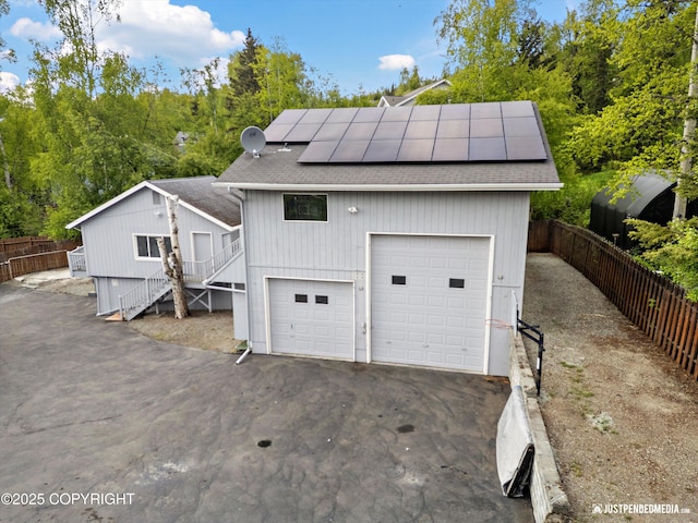10931 Adanak Cir, Eagle River, AK 99577 - back of house featuring roof with shingles, roof mounted solar panels, a garage, stairway, and driveway