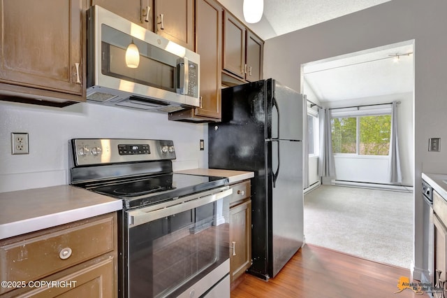 7075 Weimer Rd # 6, Anchorage, AK 99502 - kitchen with appliances with stainless steel finishes, a baseboard radiator, light wood-style floors, light countertops, and brown cabinets