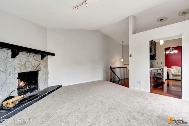 7075 Weimer Rd # 6, Anchorage, AK 99502 - carpeted living area with baseboards, a stone fireplace, track lighting, and high vaulted ceiling