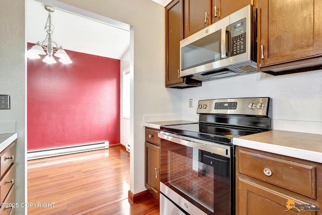 7075 Weimer Rd # 6, Anchorage, AK 99502 - kitchen with appliances with stainless steel finishes, a baseboard radiator, light wood finished floors, light countertops, and brown cabinets