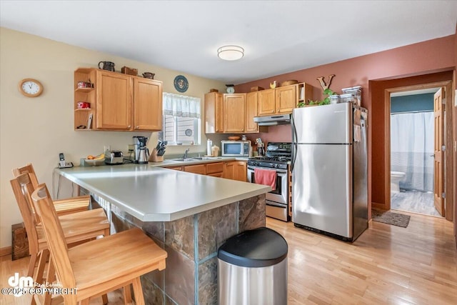 20838 Helluva St, Chugiak, AK 99567 - kitchen featuring stainless steel appliances, under cabinet range hood, light wood-style floors, light countertops, and a kitchen breakfast bar