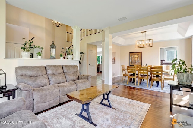 740 Botanical Heights Cir, Anchorage, AK 99515 - living room featuring wood finished floors, decorative columns, a chandelier, a tray ceiling, and baseboards
