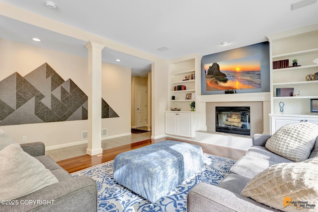740 Botanical Heights Cir, Anchorage, AK 99515 - living room with built in features, wood finished floors, a fireplace, decorative columns, and baseboards