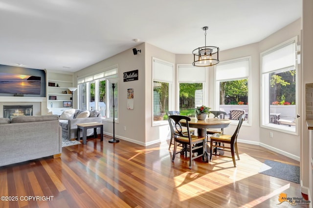 740 Botanical Heights Cir, Anchorage, AK 99515 - dining room with baseboards, a glass covered fireplace, wood finished floors, and a chandelier