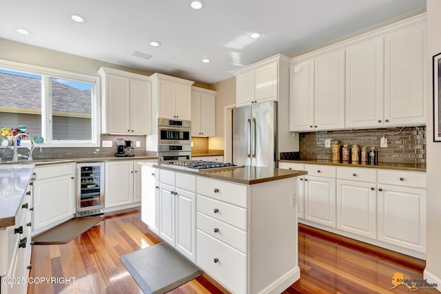 740 Botanical Heights Cir, Anchorage, AK 99515 - kitchen featuring appliances with stainless steel finishes, wine cooler, a sink, a center island, and decorative backsplash