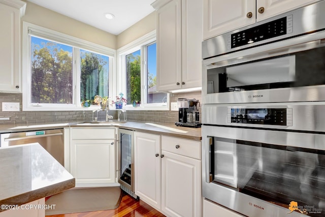 740 Botanical Heights Cir, Anchorage, AK 99515 - kitchen with appliances with stainless steel finishes, wine cooler, decorative backsplash, white cabinetry, and recessed lighting