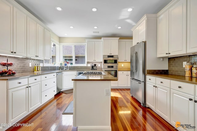 740 Botanical Heights Cir, Anchorage, AK 99515 - kitchen featuring stainless steel appliances, wood finished floors, tasteful backsplash, white cabinets, and recessed lighting