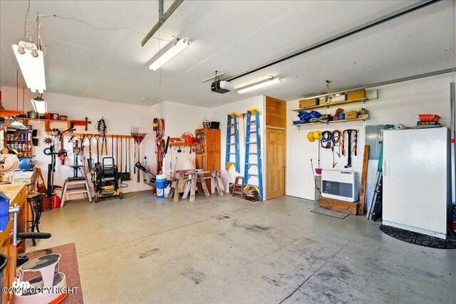 5301 N Glacier View Ct, Homer, AK 99603 - garage featuring freestanding refrigerator, a garage door opener, heating unit, and a workshop area