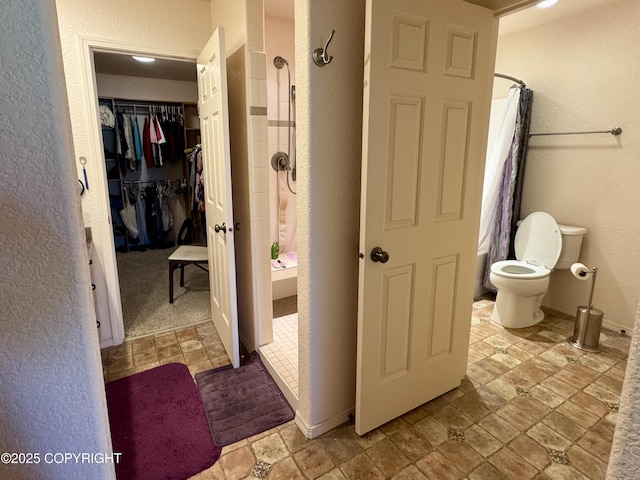 17110 E Kathy Cir, Palmer, AK 99645 - full bath featuring a textured wall, tiled shower, toilet, a walk in closet, and baseboards