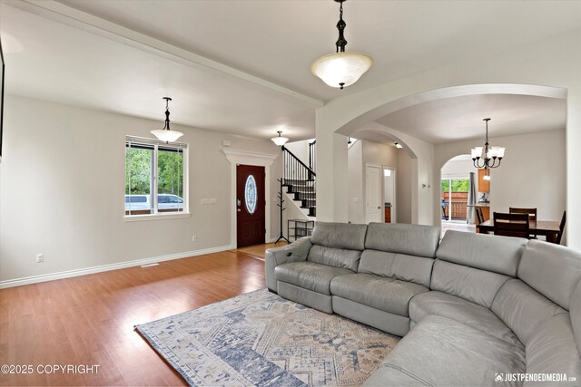 1675 E Pintail Dr, Wasilla, AK 99645 - living area featuring arched walkways, light wood finished floors, stairway, baseboards, and a chandelier