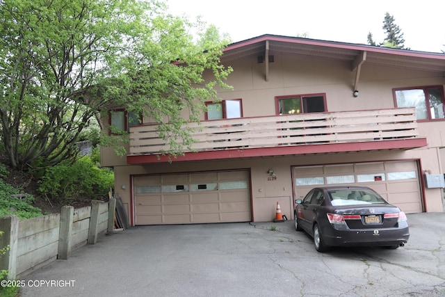 1129 W 20th Ave # 1, Anchorage, AK 99503 - rear view of house featuring an attached garage, a balcony, driveway, and stucco siding