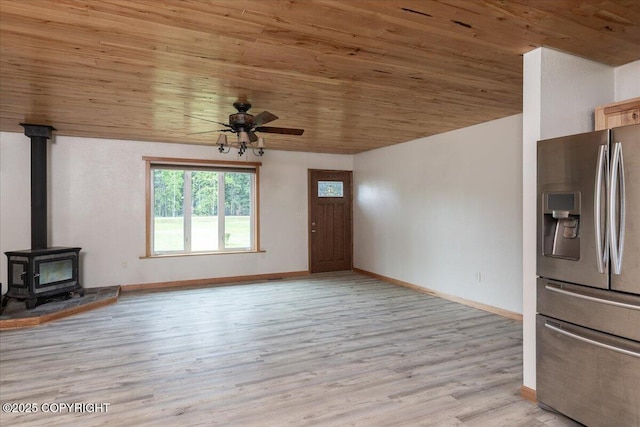 3432 Conifer Dr, North Pole, AK 99705 - unfurnished living room with wood ceiling, ceiling fan, a wood stove, light wood finished floors, and baseboards