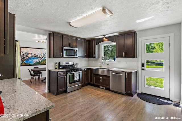 1551 S Oat St, Wasilla, AK 99654 - kitchen featuring stainless steel appliances, a sink, dark brown cabinets, a textured ceiling, and light wood finished floors
