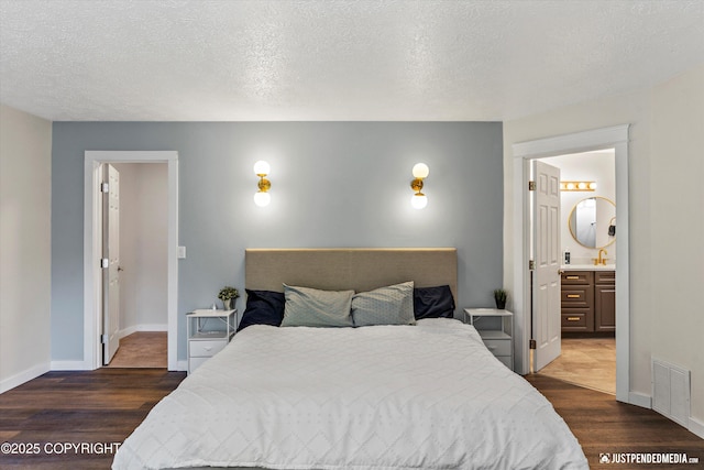 1551 S Oat St, Wasilla, AK 99654 - bedroom with dark wood-style flooring, baseboards, ensuite bathroom, a textured ceiling, and a sink