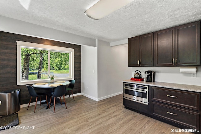 1551 S Oat St, Wasilla, AK 99654 - kitchen with stainless steel oven, light wood-style flooring, baseboards, and a textured ceiling