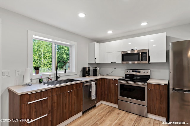 1551 S Oat St, Wasilla, AK 99654 - kitchen with stainless steel appliances, a sink, white cabinets, light wood-type flooring, and light countertops