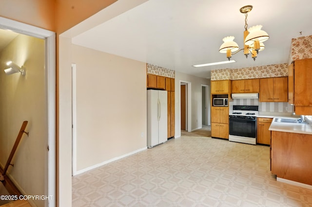 7101 Omalley Rd, Anchorage, AK 99507 - kitchen featuring white appliances, light floors, a chandelier, under cabinet range hood, and light countertops